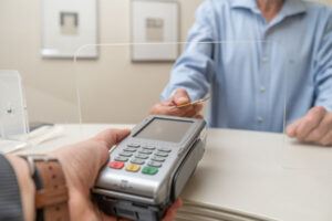 Adult man paying for visit in dentist office in the medical clinic with card