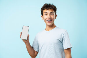 Happy teenage boy with braces holding a smartphone